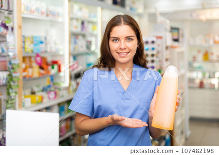 Portrait of a smiling young female pharmacist, demonstrating recently received goods for sale Portrait of a smiling young female pharmacist, demonstrating recently received goods for sale 107482198