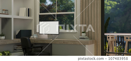A white screen computer mockup on a desk against the window in a modern home office room. 107483958