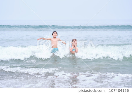 A boy and a girl are having fun playing in the sea. 107484156