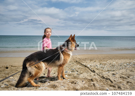 A girl in a pink T-shirt and a dog are walking. A girl in a pink T-shirt and a dog are walking. 107484159