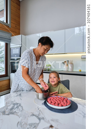 Grandmother and granddaughter preparing meatballs. Grandmother and granddaughter preparing meatballs. 107484161