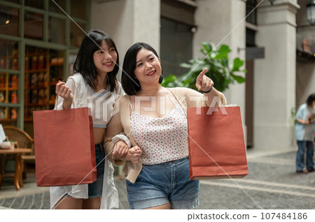 Two cheerful young Asian female friends are enjoying their shopping spree day. Lifestyle concept 107484186