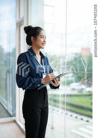 Young beautiful Asian businesswoman holding tablet while standing in the office room Young beautiful Asian businesswoman holding tablet while standing in the office room 107485208