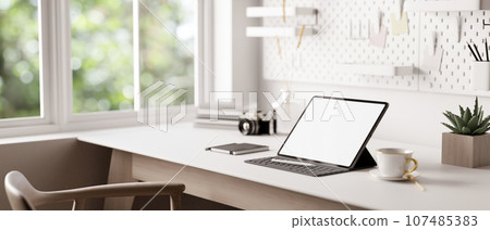 A tablet with a wireless keyboard on a white table in a minimal white home workspace. 107485383