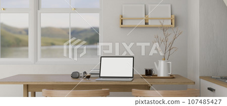 A laptop mockup on a wooden dining table in a minimalist white kitchen. 107485427