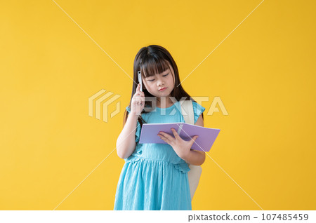 A thoughtful and cute young Asian schoolgirl is focusing on reading a book. thinking, confused A thoughtful and cute young Asian schoolgirl is focusing on reading a book. thinking, confused 107485459