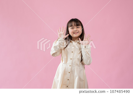 A cute little Asian girl standing with a cute peekaboo surprise posture. isolated background 107485490