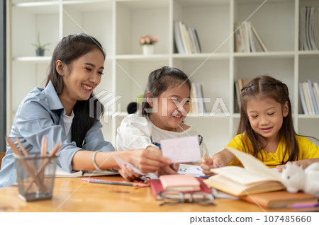Two Asian girls are enjoying studying English alphabet flashcards with a private teacher Two Asian girls are enjoying studying English alphabet flashcards with a private teacher 107485660
