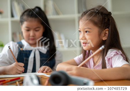 An adorable young Asian elementary school girl is focusing on studying in the classroom 107485729