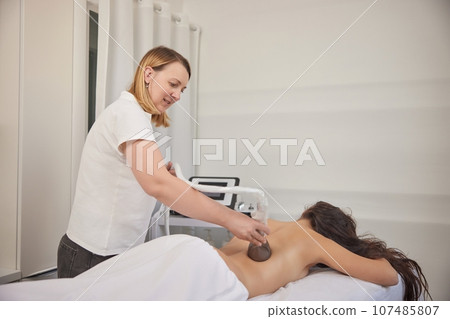 professional equipment, receiving massage, Applying vacuum. Massage of body with vacuum, problem areas slimming using professional equipment, lpg massage, anti-cellulite roller-vacuum massages professional equipment, receiving massage, Applying vacuum. Massage of body with vacuum, problem areas slimming using professional equipment, lpg massage, anti-cellulite roller-vacuum massages 107485807