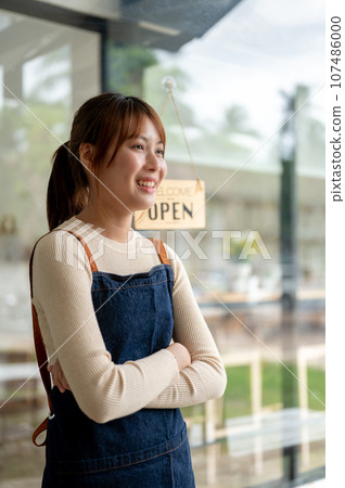 A pretty Asian female coffee shop owner standing with her arms crossed at the entrance door A pretty Asian female coffee shop owner standing with her arms crossed at the entrance door 107486000
