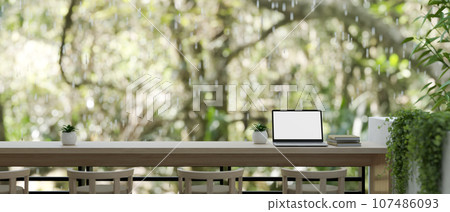 A laptop on a tabletop on a balcony or terrace with a beautiful nature view on a rainy day. 107486093