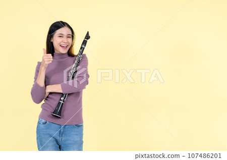 A beautiful and talented Asian woman holding a clarinet and showing her thumb up 107486201