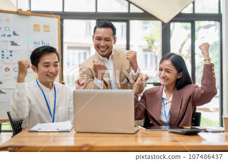 A group of cheerful Asian businesspeople are rejoicing in their project success together. A group of cheerful Asian businesspeople are rejoicing in their project success together. 107486437