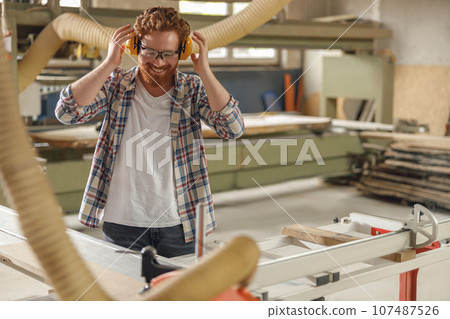 Professional carpenter cutting wooden board at sawmill carpentry manufacturing . Sawing machine 107487526