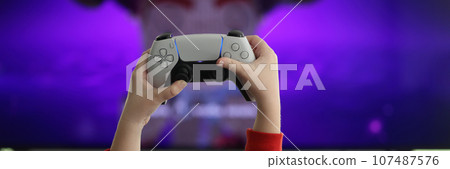 Hands of little girl holding game console against screen 107487576