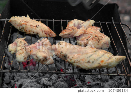 Chicken Fillet Bbq. Grilled Chicken Breast on the hot Grill with Smoke and Fire Flames. Juicy White Meat Steak. Delicious Poultry Roasted Cooked on a Charcoal Barbecue. Camping Food. Outdoors Cooking 107489184