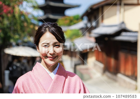 A young woman in a kimono standing with a five-storied pagoda in the background 107489583