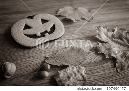 Halloween still life, sepia. Autumn leaves and pumpkin figure with nuts. Halloween decoration on wooden table. Creepy decoration. October still life. The fall season concept. Halloween still life, sepia. Autumn leaves and pumpkin figure with nuts. Halloween decoration on wooden table. Creepy decoration. October still life. The fall season concept. 107490457