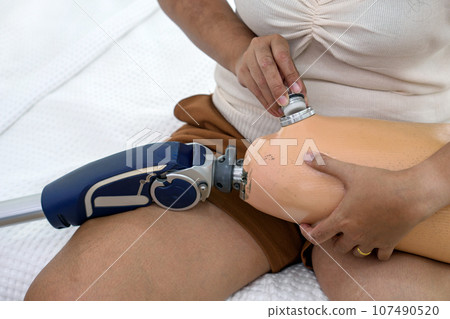 Determined woman expertly navigating a high-tech device on her leg, suggesting healthcare tech use. 107490520