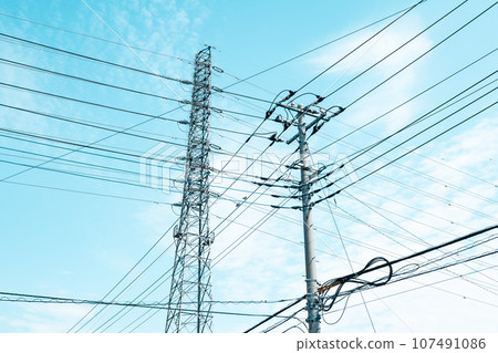 Intersecting high-voltage power lines, electric wires in residential area, and autumn sky, light tone 107491086