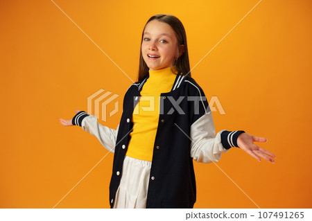 Puzzled teen girl don't know what to do on yellow background in studio Puzzled teen girl don't know what to do on yellow background in studio 107491265