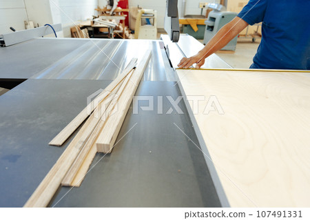 Close up of male carpenter working with piece of wood in a workshop Close up of male carpenter working with piece of wood in a workshop 107491331