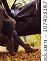 Women's legs in jeans and cowboy boots from an opened car. 107493167