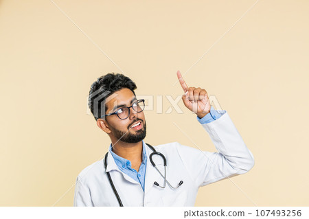Doctor man showing thumbs up and pointing on blank space place for advertisement promotion logo Doctor man showing thumbs up and pointing on blank space place for advertisement promotion logo 107493256