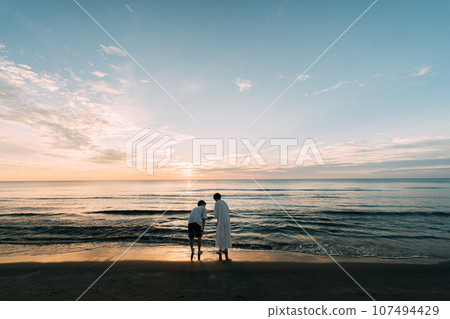日落和一對夫婦在海中沉沒 107494429