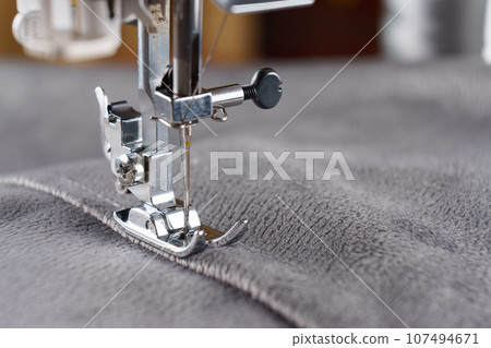 Modern sewing machine with gray velours fabric close up Modern sewing machine with gray velours fabric close up 107494671