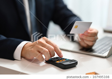 Businessman calculating expenses and debt from credit cards on office desk. E-commerce, financial planning and expenses 107495108