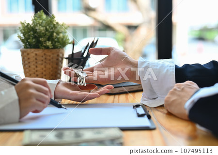 Realtor or landlord giving keys to client after sign agreement or sale purchase contract. Real estate and property investment concept 107495113