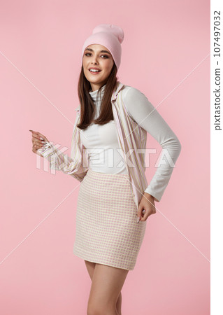 Happy playful young woman in pink hat, shirt and skirt 107497032
