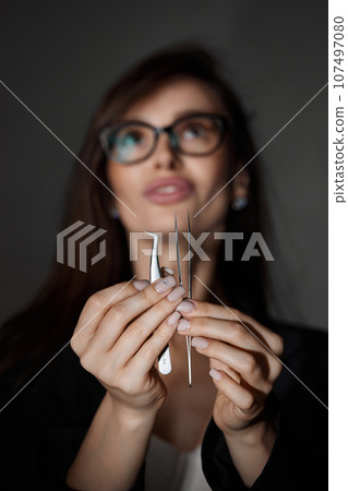 beautiful woman holding eyelashes tweezers on black background beautiful woman holding eyelashes tweezers on black background 107497080