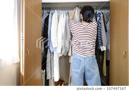 一個女人從衣櫃裡拿出衣服。該換衣服了。 一個女人從衣櫃裡拿出衣服。該換衣服了。 107497167