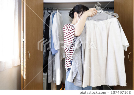 女人在衣櫃前拿著衣服 女人在衣櫃前拿著衣服 107497168
