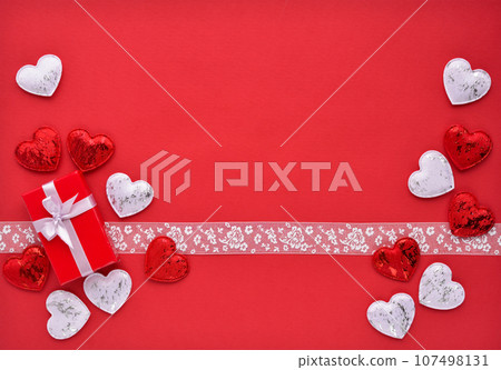 Valentines Day background. Red gift box with ribbon and hearts on a red background. Top view. 107498131