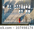 Top down view of a parking lot with generic white cars and one red car  107498174