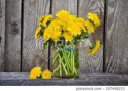 Bouquet of dandelion flowers, yellow wildflowers on old wooden table. Still life with wild flowers 107498251