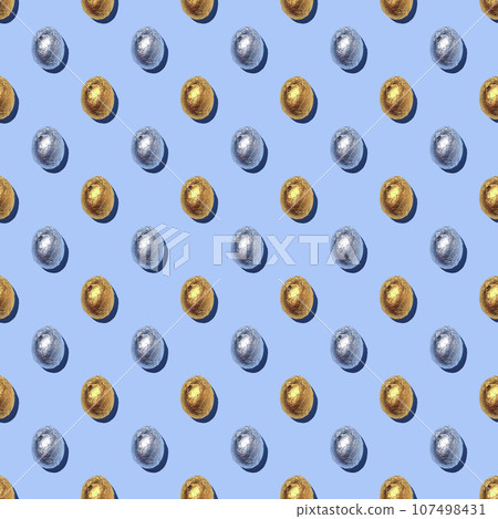 Seamless Pattern of sparkly chocolate foil eggs on blue background. Seamless Pattern of sparkly chocolate foil eggs on blue background. 107498431