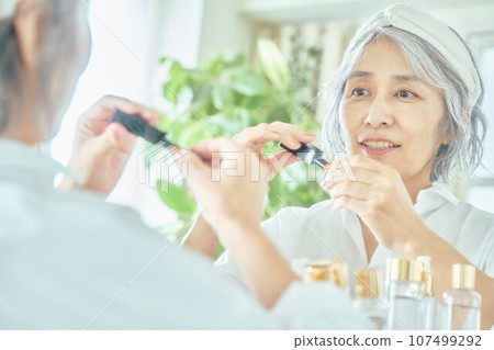 Senior woman applying lipstick Senior woman applying lipstick 107499292
