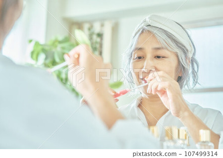 Senior woman applying lipstick Senior woman applying lipstick 107499314