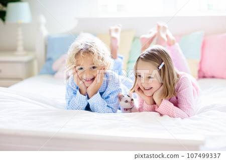 Kids play with baby cat. Child and kitten in bed. Kids play with baby cat. Child and kitten in bed. 107499337