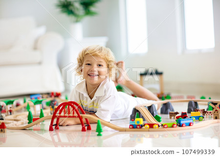 Kids play wooden railway. Child with toy train. Kids play wooden railway. Child with toy train. 107499339