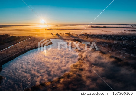 Lake with view from height of fog in early autumn morning sun on horizon Lake with view from height of fog in early autumn morning sun on horizon 107500160