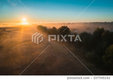 Beautiful sunrise on autumn morning with picturesque fog of trees and elephant on horizon 107500282