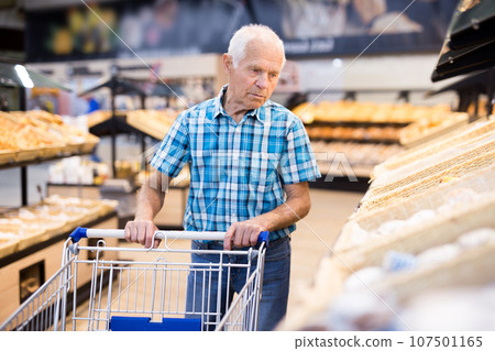 Mature senor choosing bread and baking in grocery section of supermarket 107501165