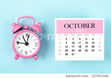 The October 2023 Monthly calendar for 2023 year with pink color alarm clock on blue background. 107501446