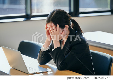 Young woman covering her face and thinking while working Young woman covering her face and thinking while working 107501762